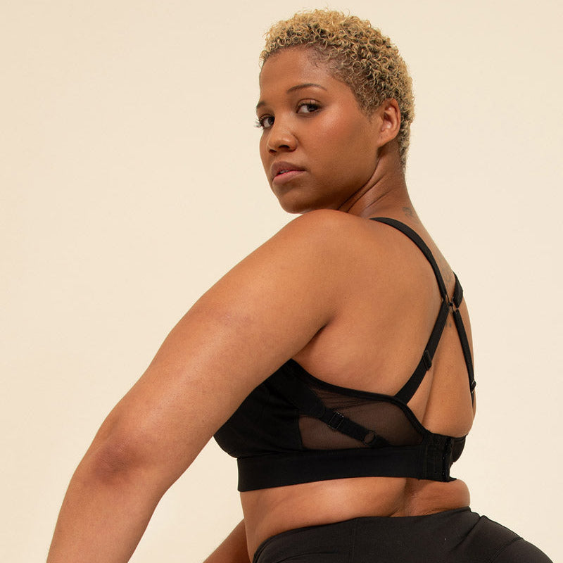 Woman wearing a black sports bra and leggings against a beige background