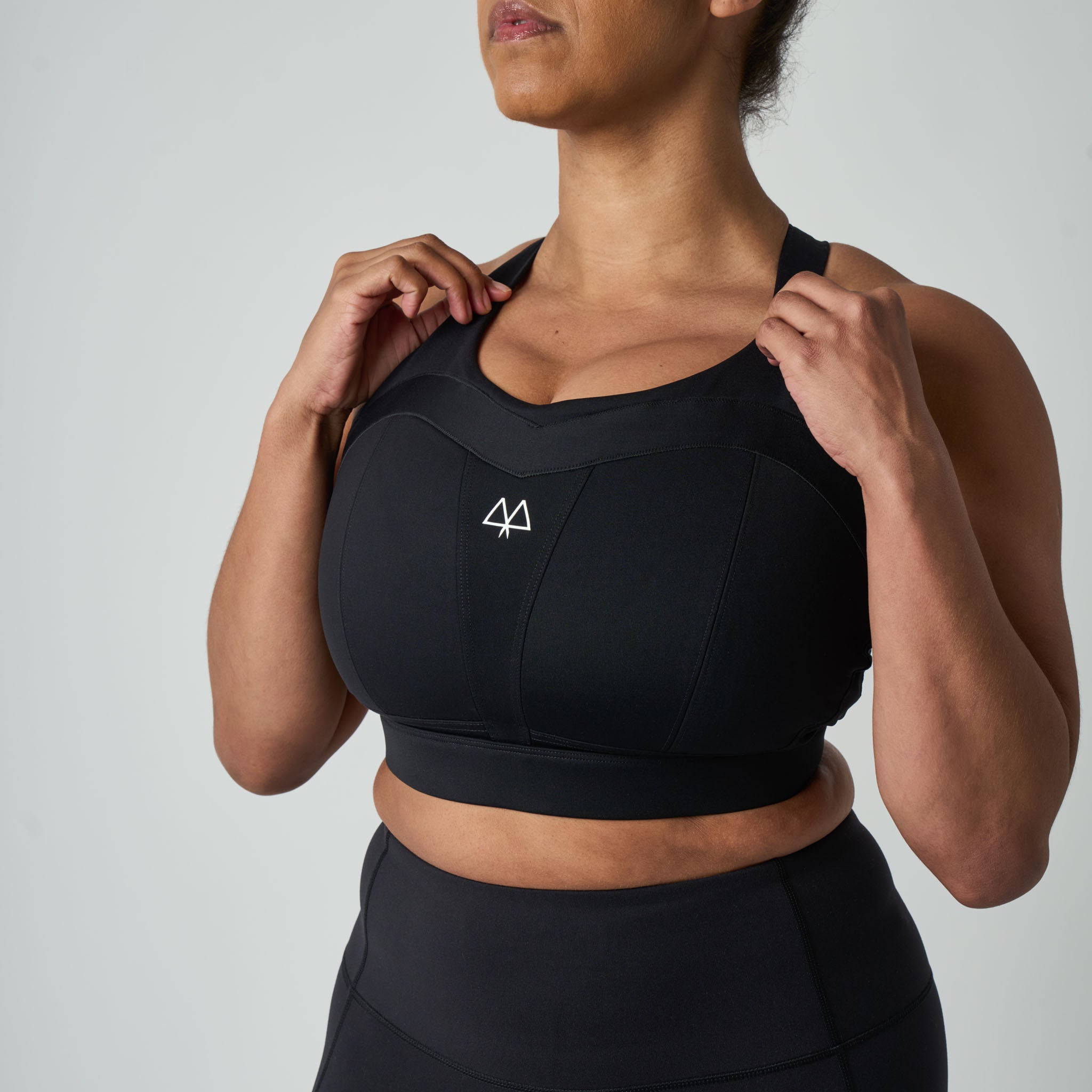 Person wearing a black sports bra with a logo on a light gray background