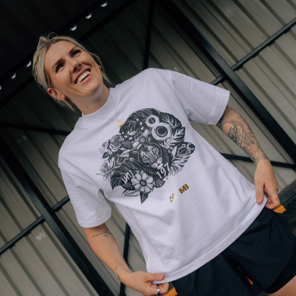 England Footballer Millie Bright wearing a white t-shirt with a black graphic design, standing on a staircase.