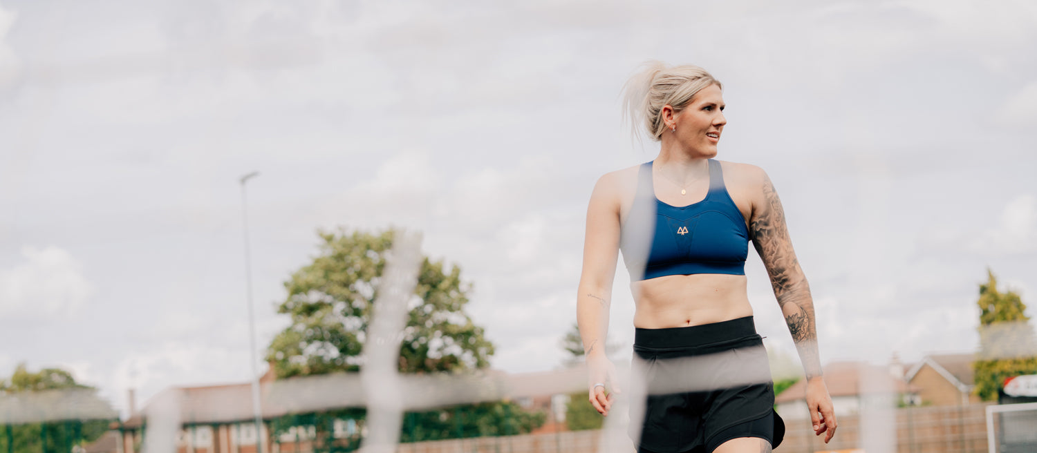 Woman in athletic wear standing outdoors with a blurred background