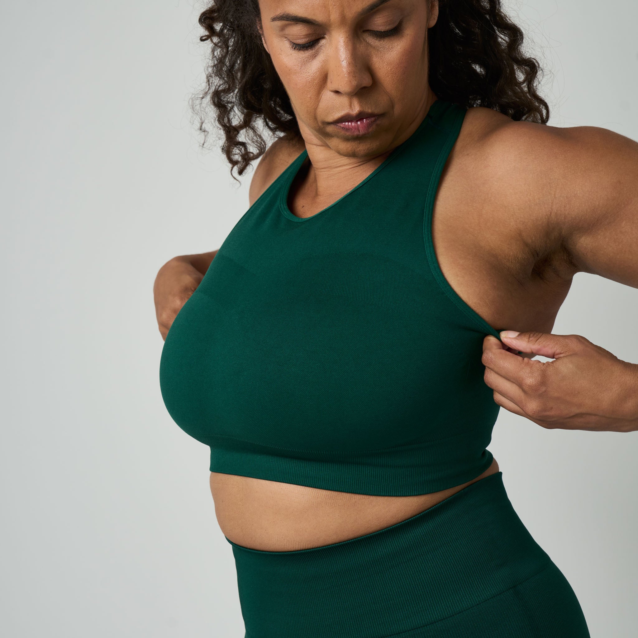 Woman wearing a green sports bra and leggings against a plain background