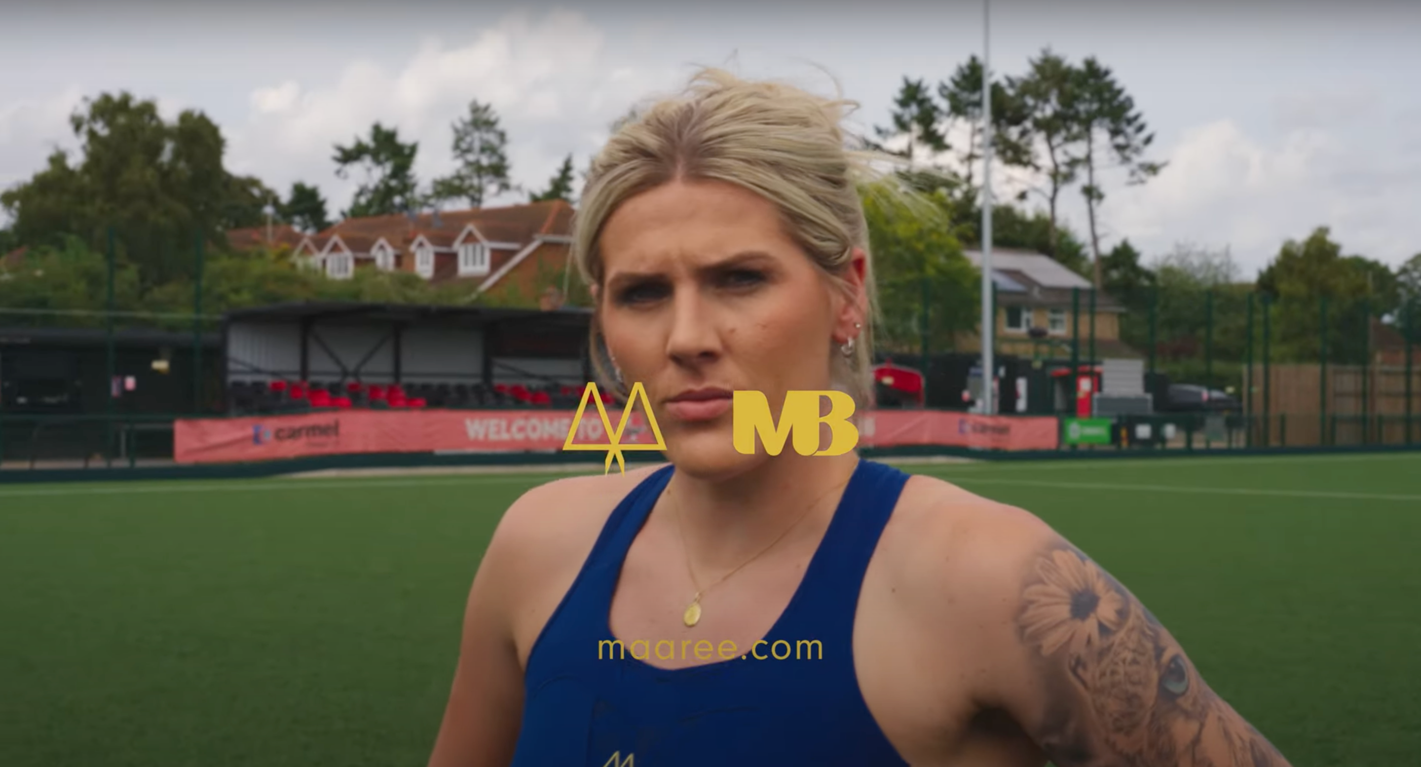 Millie Bright in a MAAREE blue sports bra standing on a field with 'MB' logo overlay