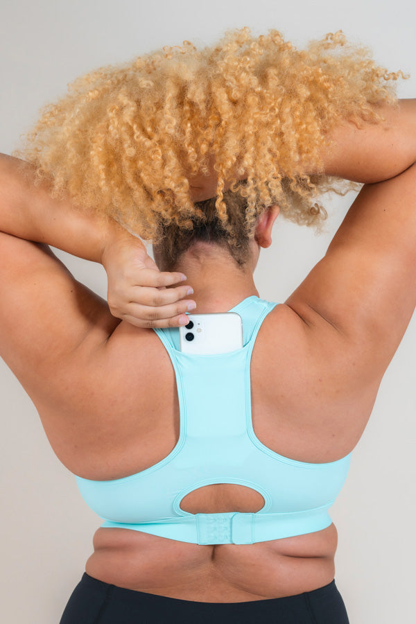 Woman wearing MAAREE Empower Sports Bra in Spearmint Green colour putting phone in the back pocket